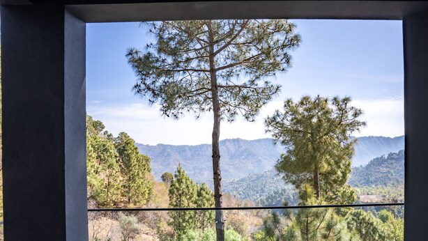 Un balcón con sillas de mimbre, una mesa con bebidas y vistas a la montaña.