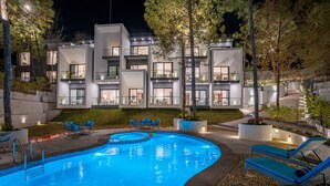 Un hotel moderno con piscina, zona de estar exterior y balcones bien iluminados.