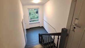 Una escalera con barandilla, una puerta a la derecha y un ventanal en la parte superior.