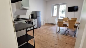 Eine moderne Küche mit Einbauofen, Kühlschrank und einem Essbereich mit Tisch und Stühlen.