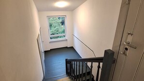 Una escalera con barandilla que conduce a un rellano con ventana con vistas a follaje.