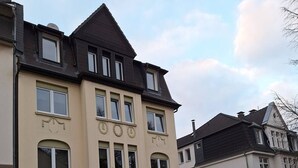 Un edificio residencial de varios pisos con fachada simétrica, ventanas amplias y una entrada central.