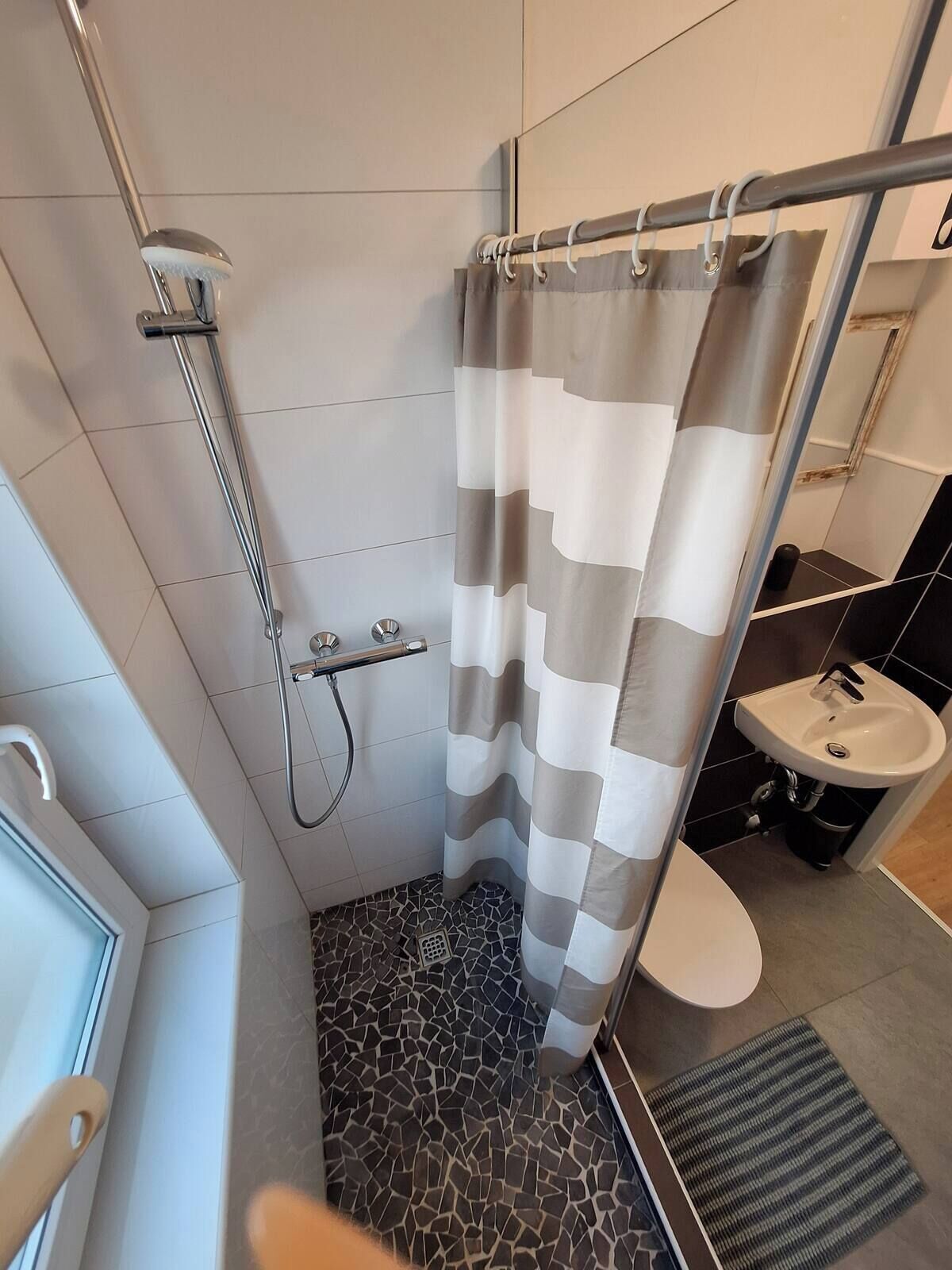 Un bany modern amb dutxa, vàter i rentapans.