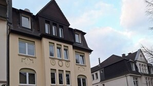 Un immeuble résidentiel à plusieurs étages, doté d’une façade symétrique, de grandes fenêtres et d’une entrée centrale.