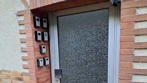 Une porte dotée d’un clavier de sécurité, d’un cadre métallique et d’un panneau en verre texturé.