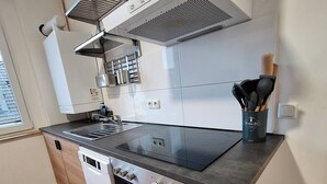 A modern kitchen with a built-in stove, oven, and dishwasher, featuring a sleek countertop and wooden flooring.