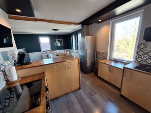 A modern kitchen with wooden cabinets, a central island, and a large window providing natural light. - Große 5-zimmer-wohnung in Zentraler Lage in Oerlinghausen für 8 Personen (Oerlinghausen)