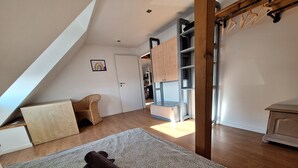Ein Schlafzimmer im Loft-Stil mit schrägem Dach, einem gemusterten Teppich und einem Holzstuhl.