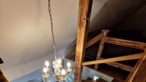 Eine Holztreppe mit einem Chandelier in einem Raum mit Holzbalken und einer geneigten Decke.