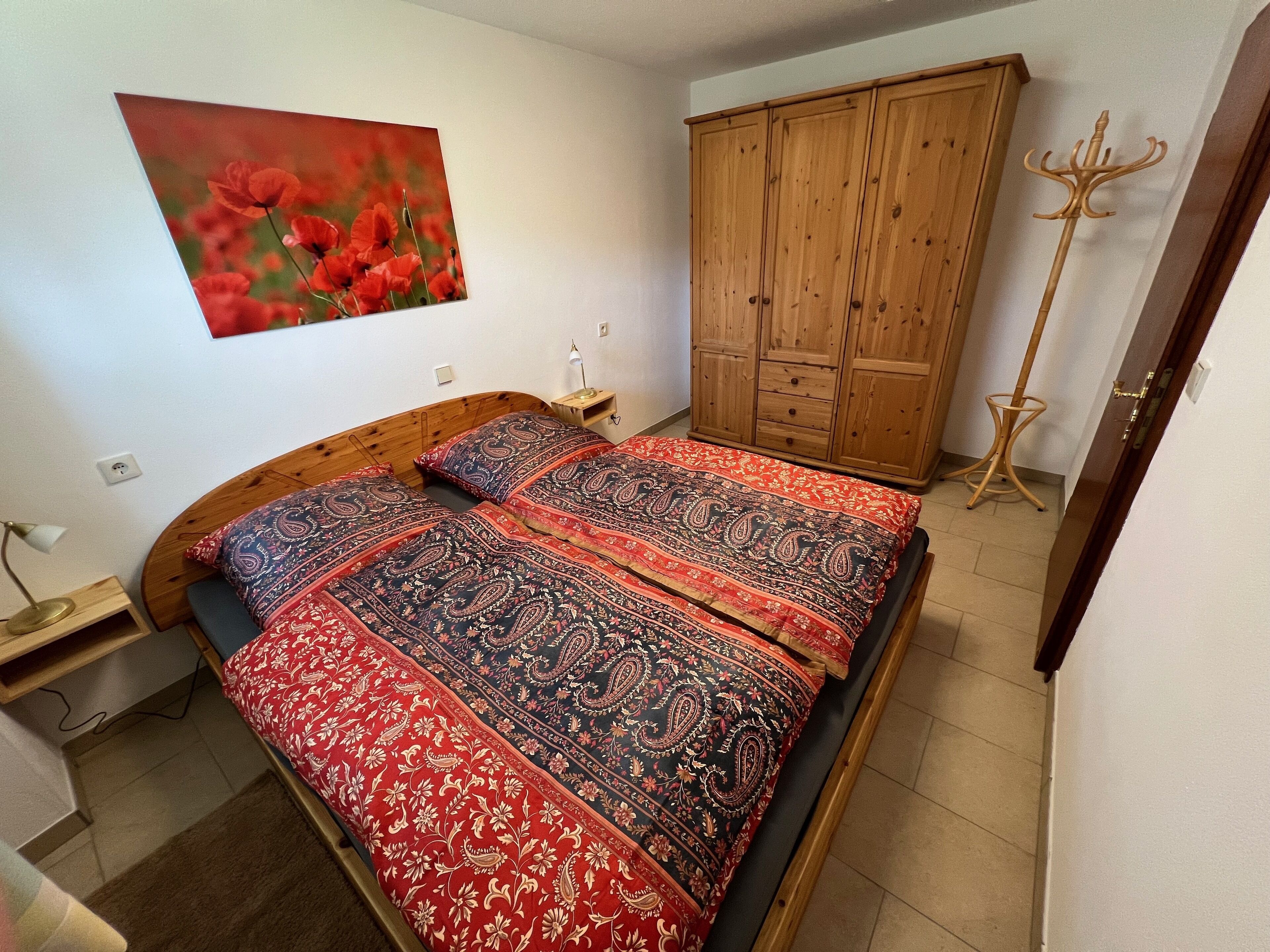 Ein Schlafzimmer mit einem hölzernen Bett, einem großen Kleiderschrank und einer Stehlampe.