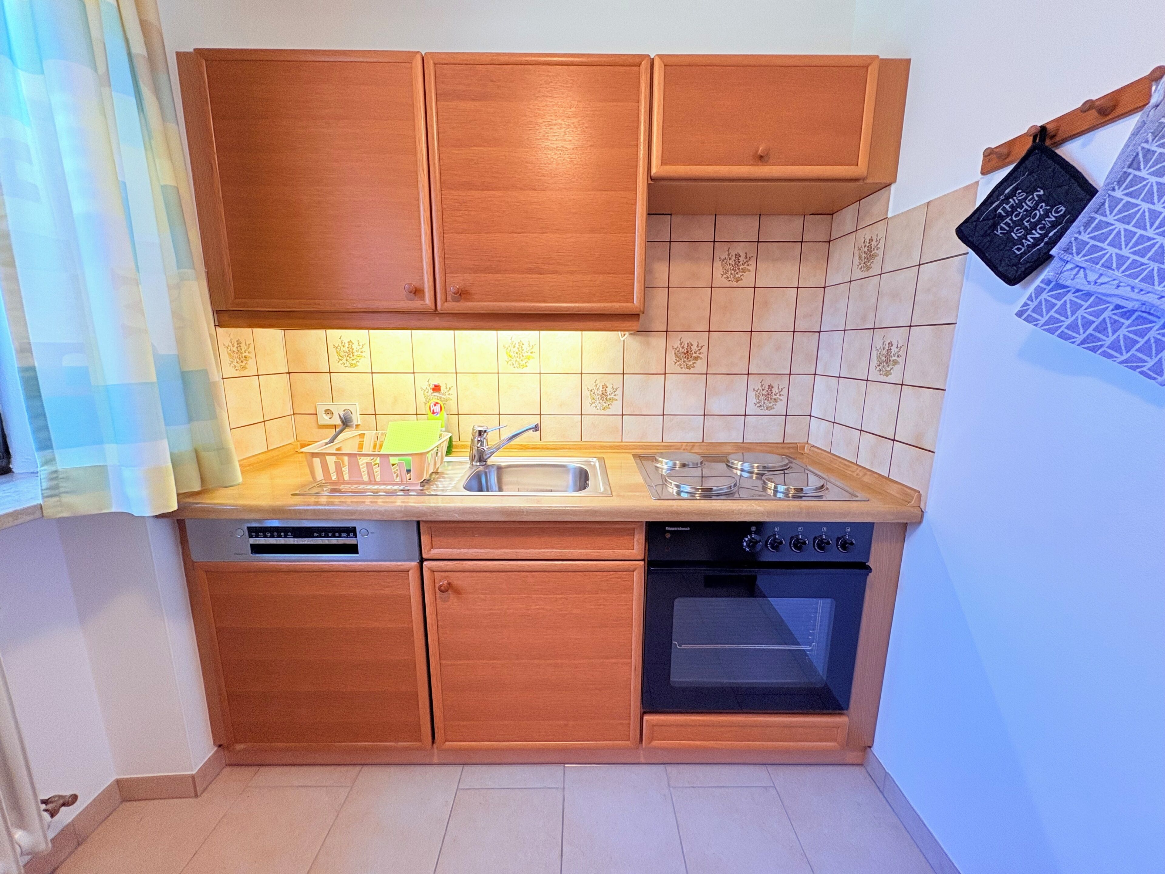 Una cocina compacta con armarios de madera, lavavajillas integrado, estufa y microondas.