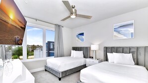Une chambre d’hôtel avec deux lits, un ventilateur de plafond, une grande fenêtre donnant sur un beau paysage et des œuvres d’art accrochées aux murs.