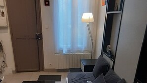 A modern living room with a sofa, a coffee table, and a lamp. - Apartment Studio in Small renovated house in Paris (Paris)