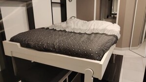 A bed with a patterned bedspread and a white lace-trimmed pillow. - Apartment Studio in Small renovated house in Paris (Paris)