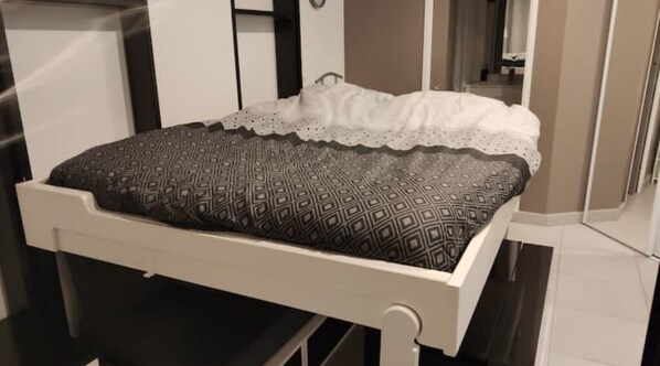 A bed with a patterned bedspread and a white lace-trimmed pillow. - Apartment Studio in Small renovated house in Paris (Paris)