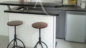 A kitchen with a black countertop, two stools, and red cabinets. - Apartment Studio in Small renovated house in Paris (Paris)
