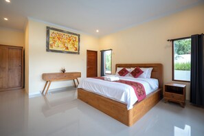A spacious bedroom with a large bed, a wooden nightstand, a bedside table, and a wardrobe. - The Patra Ubud (Ubud)
