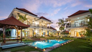 Uma casa moderna com dois andares, piscina, varanda coberta e gramado bem cuidado.