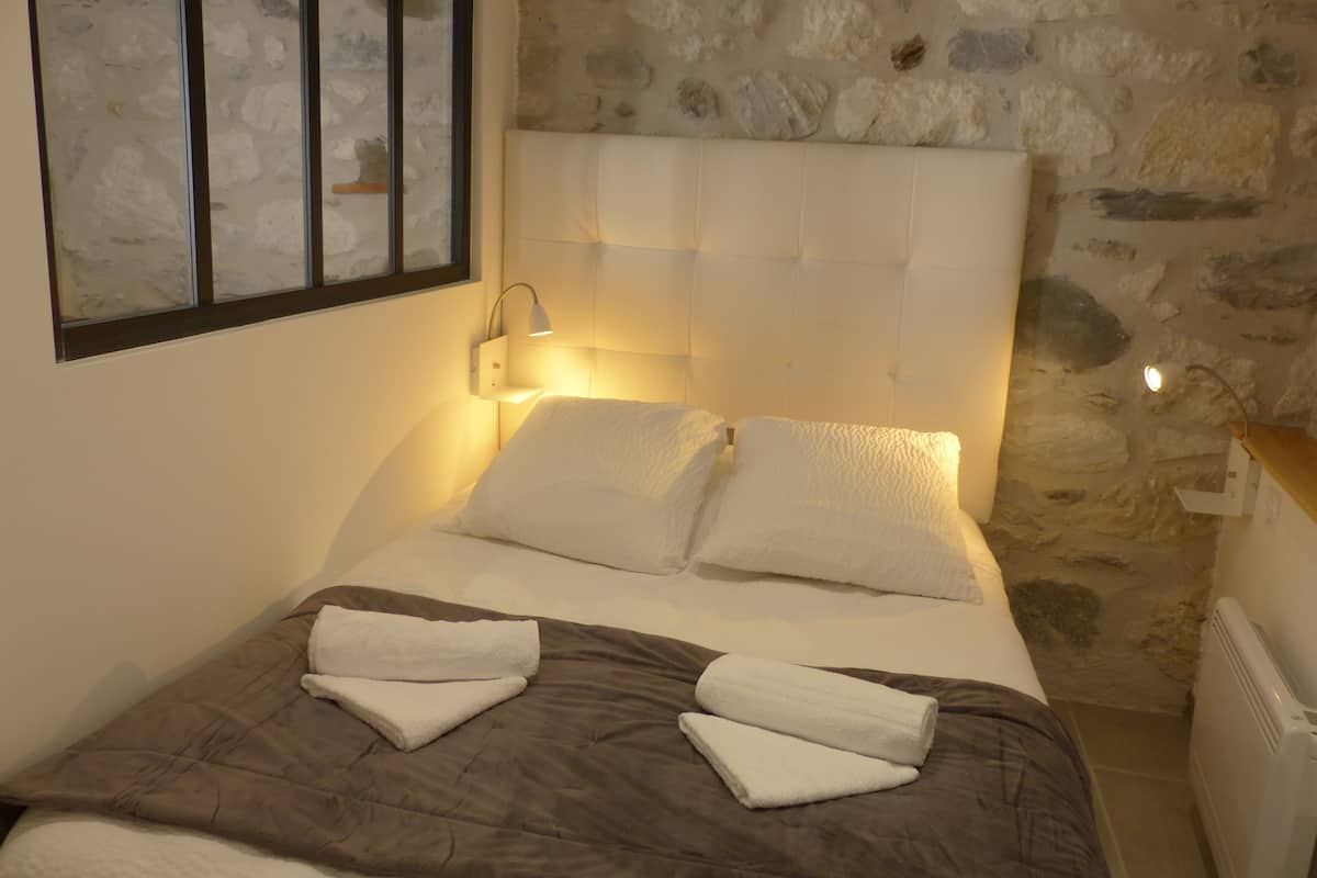 A bed with a headboard, two pillows, and two folded towels.