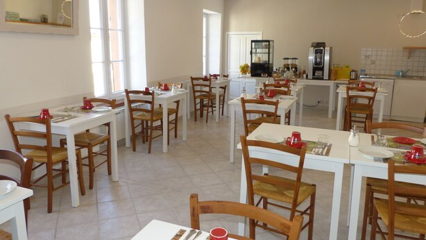 Un comedor con varias mesas y sillas, una cocina al fondo y un espejo grande en la pared.