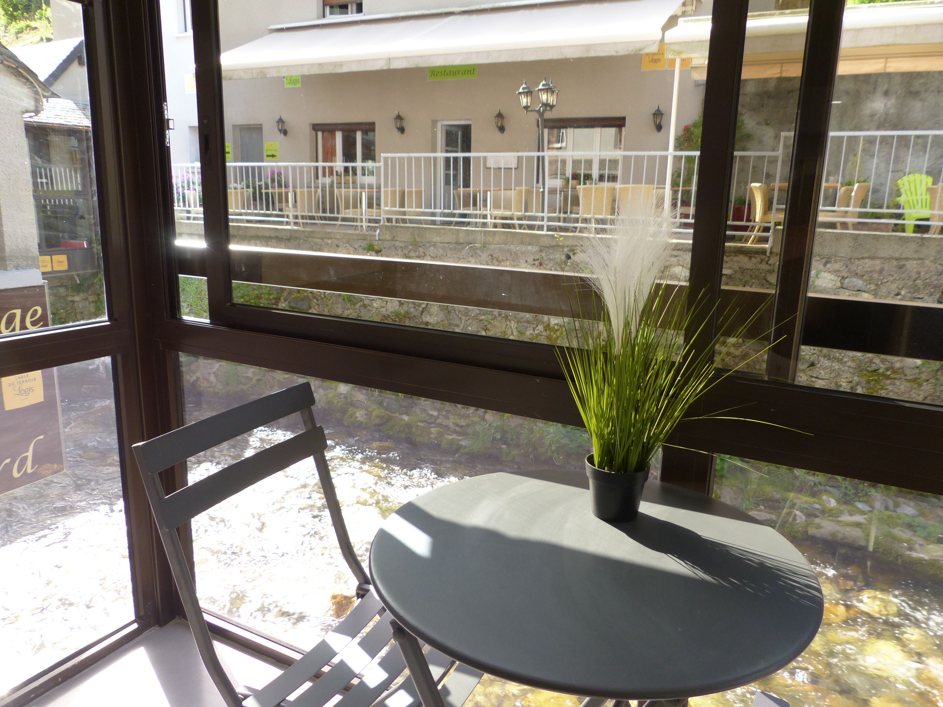 A room with a view of a restaurant and a small outdoor area with a table and chair.