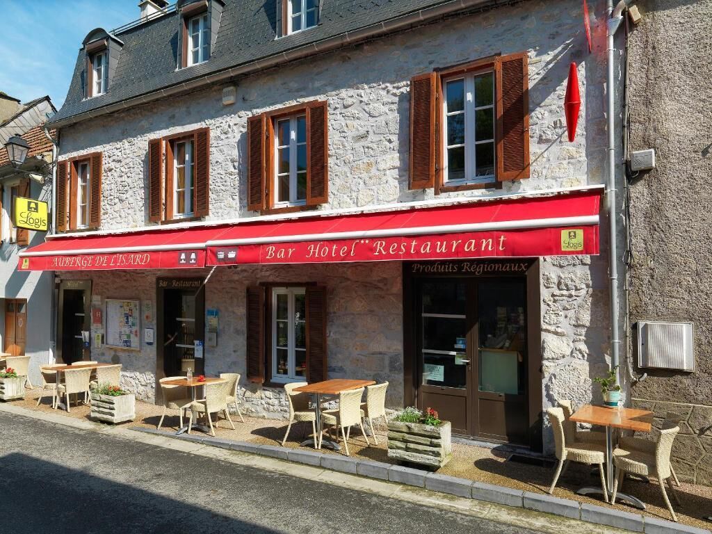 Hotel, bar og restaurant med udendørs siddepladser og en facade af sten.