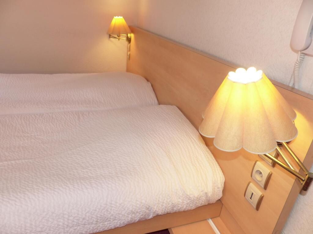 A hotel room with a bed, a bedside lamp, and a telephone.