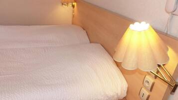 A hotel room with a bed, a bedside lamp, and a telephone.
