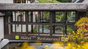 Restaurante de hotel con vista a un arroyo y follaje verde.