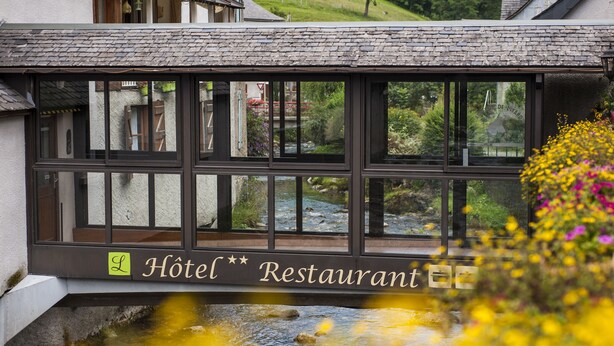 A hotel restaurant with a view of a stream and greenery. - Hotel Auberge de l'Isard (Saint-Lary)
