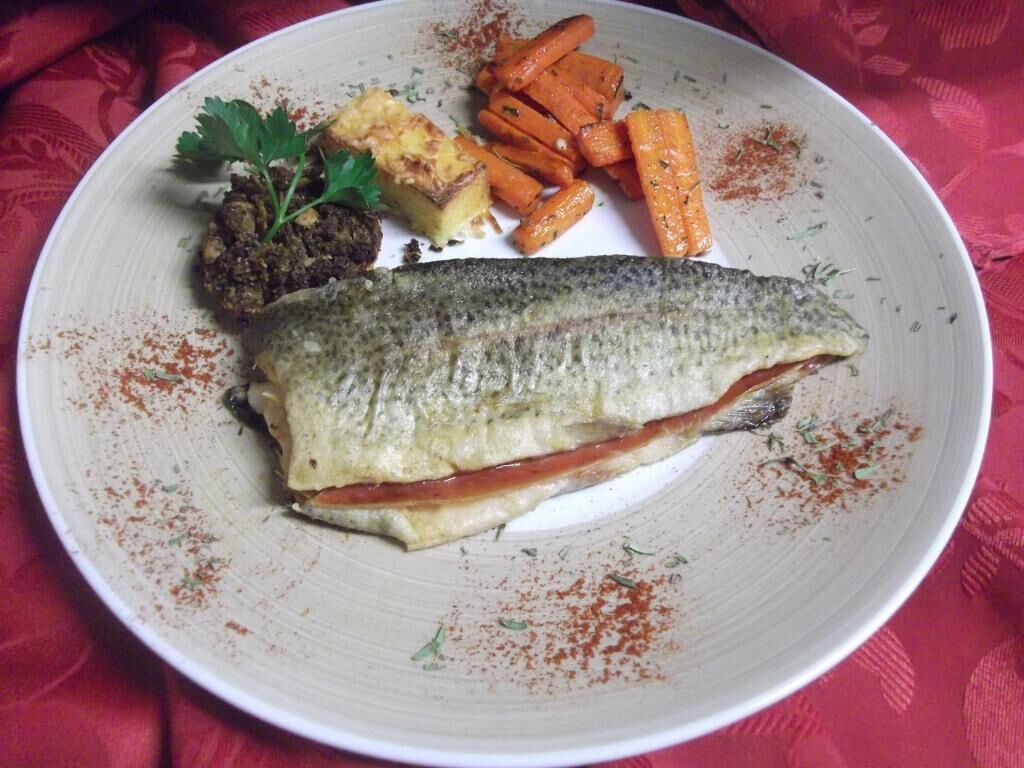 A plate with a fish, carrots, and a side dish.