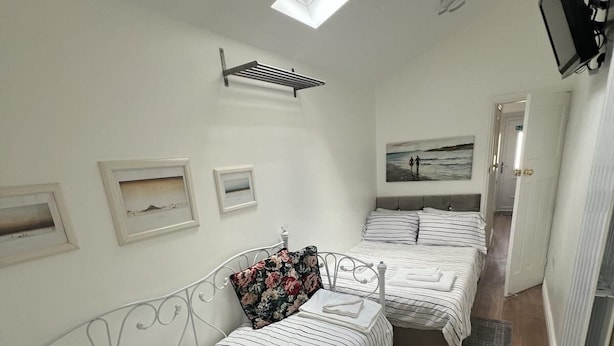 Een kamer met een bed, een slaapbank, een eettafel, een aan de muur bevestigde televisie en een plafondlamp.