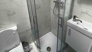Een moderne badkamer met een douchecabine van glas, een toilet en een wastafel met kastje.