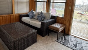 A cozy room with a sofa, a bench, and a wicker coffee table. - River House & Fishing (Elk River)