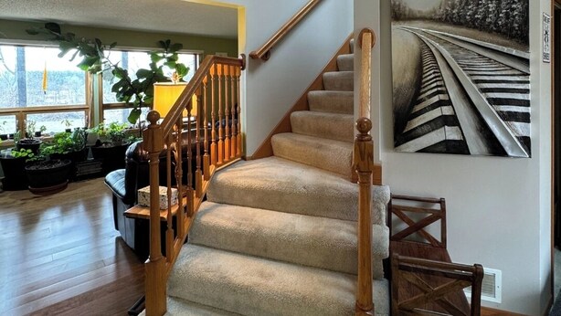 A staircase with wooden railings and carpeted steps leading to a second floor. - River House & Fishing (Elk River)