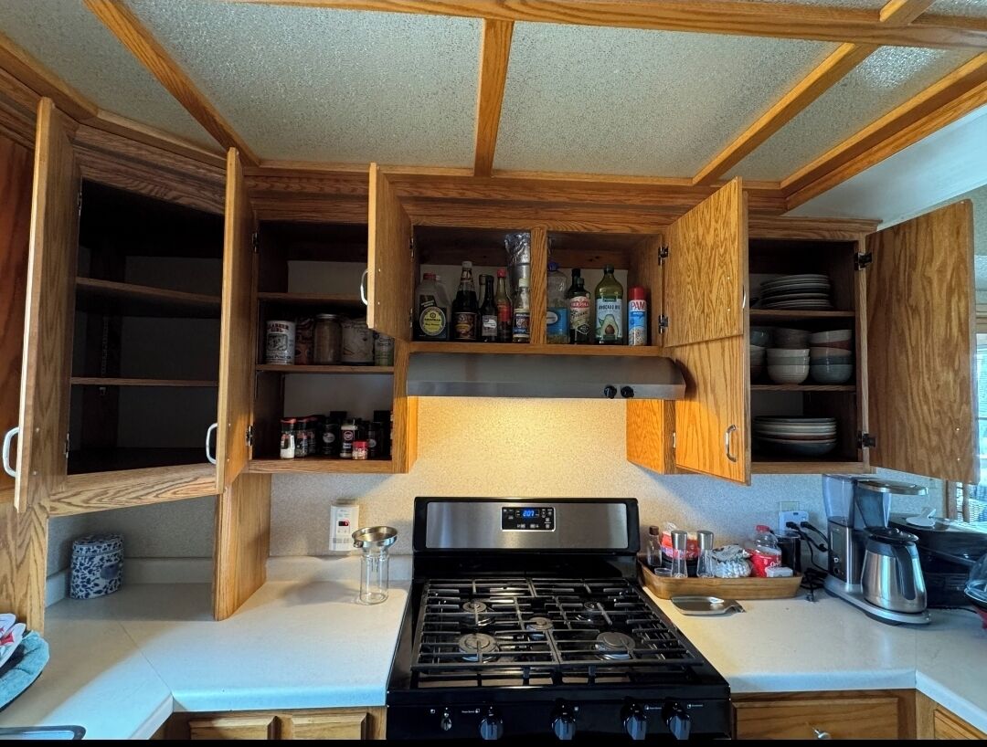 A compact kitchen with wooden cabinets, a gas stove, and various kitchen appliances.