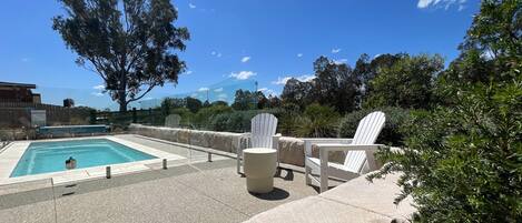 Piscina com espreguiçadeiras e um banco de pedra.