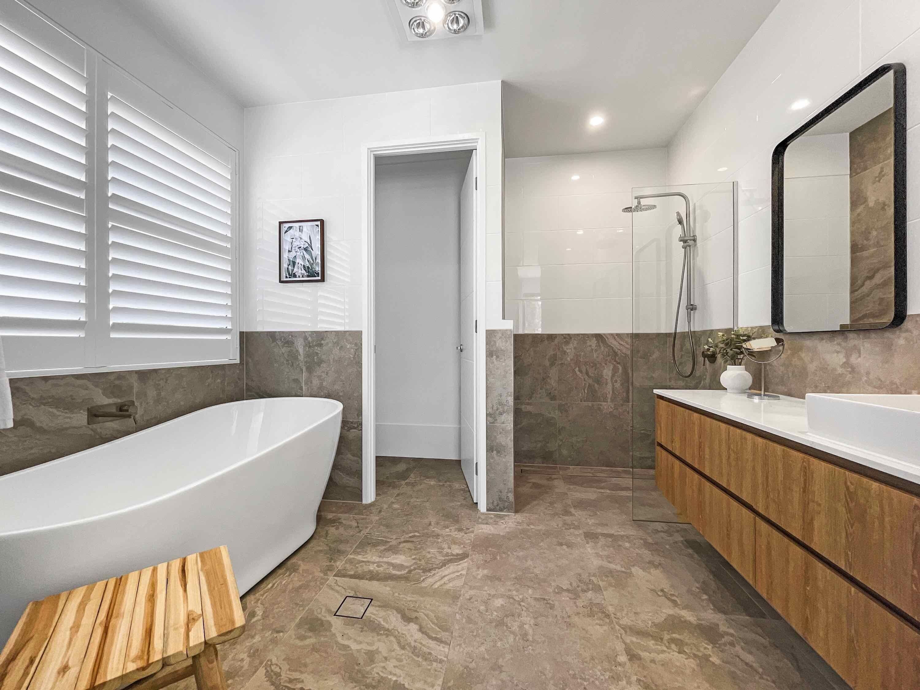 Een moderne badkamer met een vrijstaand bad, een wastafel met spiegel en een douchegedeelte.