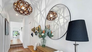 Ein Flur mit einer hölzernen Bank, einem Schreibtisch mit Lampe, einem Spiegel und an der Wand befestigten Hüten.