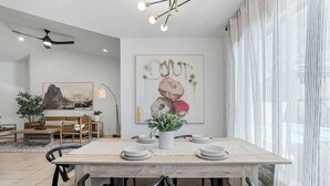 A dining area with a wooden table, black chairs, and a white vase with green plants.