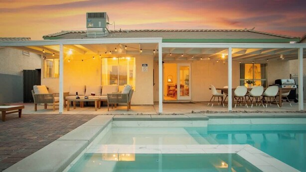 A covered outdoor area with a pool, seating, and a barbecue setup.