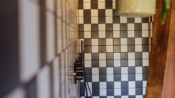 A bathroom with a checkered tile floor, a hanging plant, and a towel rack.