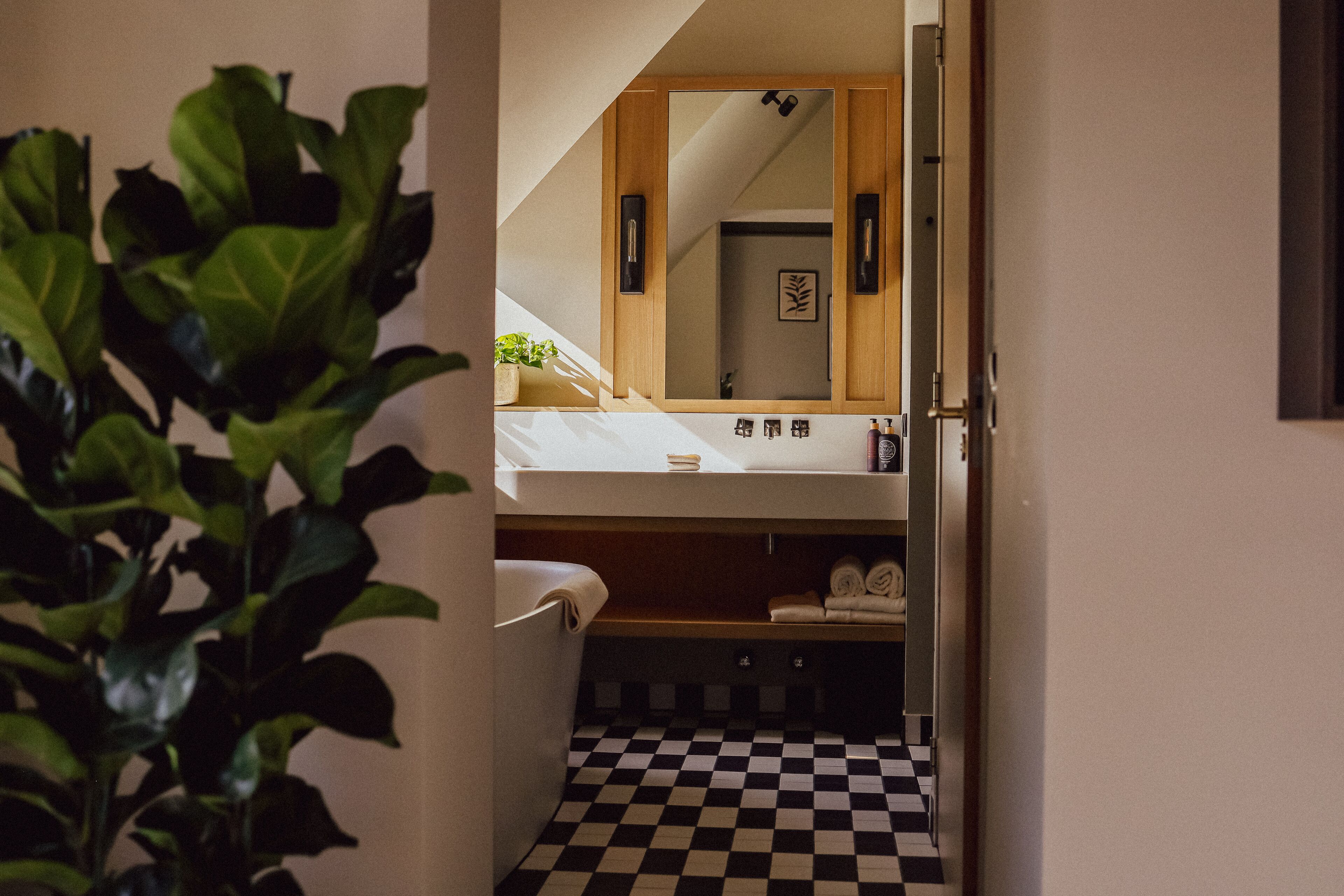 A bathroom with a checkered floor, a sink, and a mirror.