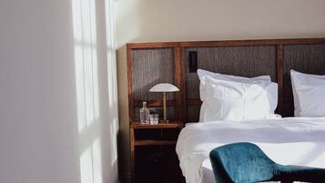 A hotel room with a bed, a nightstand with a lamp, a chair, and a patterned rug.