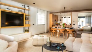A modern living room with a flat-screen TV, a dining area with wooden furniture, and a large mirror reflecting the space. - Majestic Villa Lidija w/ private infinity pool and sea view  (Dubrovnik)