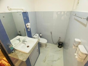 A bathroom with a sink, toilet, and shower. - Hotel The White Castle (Kargil)