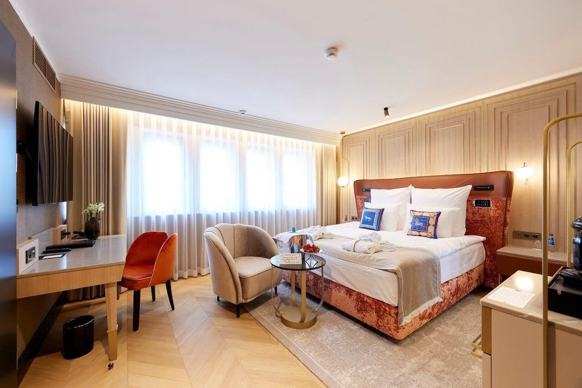 Een hotelkamer met een bed, een bureau, een stoel, een tafeltje en een televisie.