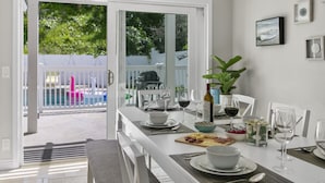 A dining area with a table set for two, including plates, glasses, and a bowl of fruit. - Stunning Coastal Escape w. private pool & spa, arcade, near themed parks & beach (Mission Viejo)