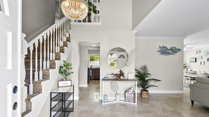 A spacious foyer with a grand staircase, a chandelier, and a dining area. - Stunning Coastal Escape w. private pool & spa, arcade, near themed parks & beach (Mission Viejo)