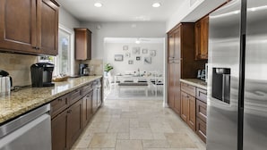 A modern kitchen with granite countertops, stainless steel appliances, and wooden cabinetry. - Stunning Coastal Escape w. private pool & spa, arcade, near themed parks & beach (Mission Viejo)